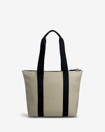 A structured tote bag in light beige with two prominent black vertical side straps and black shoulder handles, shown against a plain white background.