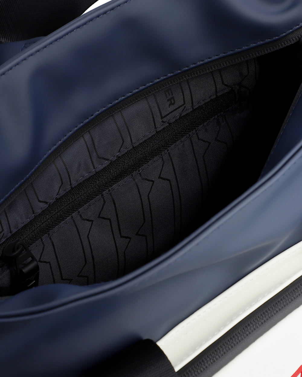 Close-up of a navy blue bag interior showing a black zippered pocket with a textured geometric pattern lining.
