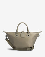 A light beige tote bag with dual top handles, a matching adjustable shoulder strap, and a small front flap detail, photographed against a clean off-white background.