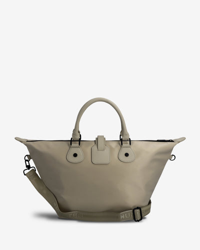 A light beige tote bag with dual top handles, a matching adjustable shoulder strap, and a small front flap detail, photographed against a clean off-white background.