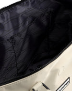 Close-up of the interior of a Hunter bag, showing a black zippered compartment with a black patterned lining and a cream-colored exterior.