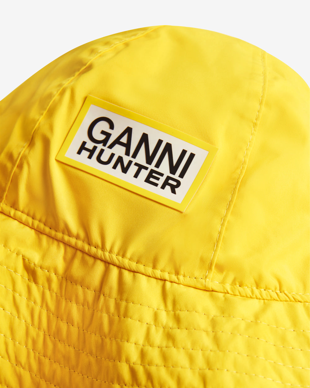 Displays the lemon 'Hunter' branded unisex GANNI X Hunter Waterproof Bucket Hat featuring the Ganni x Hunter logo