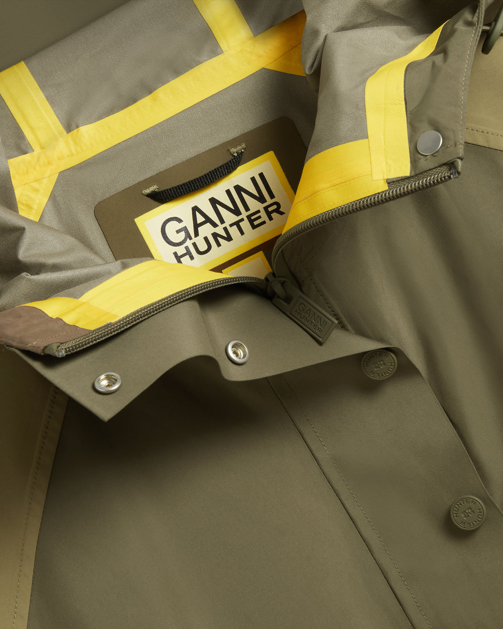 Displays the Green 'Hunter' branded Unisex GANNI X Hunter Waterproof Poncho featuring the details including the Ganni x Hunter logo branding 
