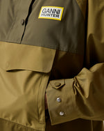 Displays a model wearing the Green 'Hunter' branded Unisex GANNI X Hunter Waterproof Poncho featuring the details including the Ganni x Hunter logo branding 