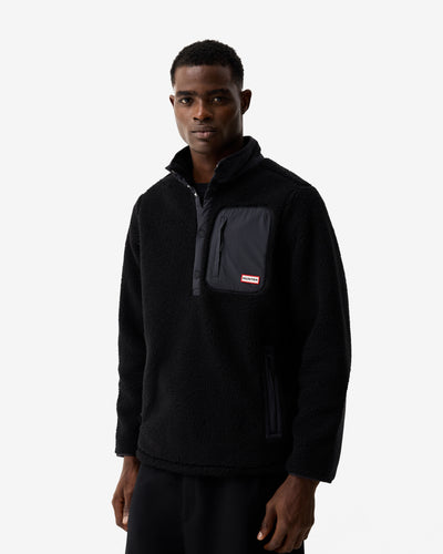 Man wearing a black pullover with a visible brand logo on a white background