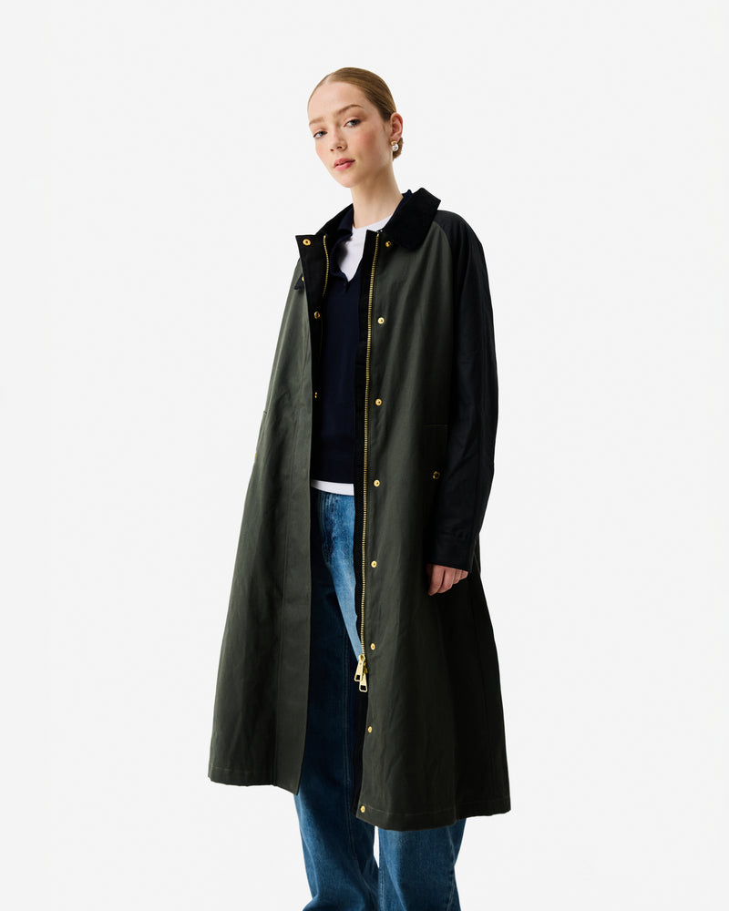 Displays a model wearing the Kambaba Green 'Hunter' branded Women's Harrow Patch Colour Block Long Waxed Jacket