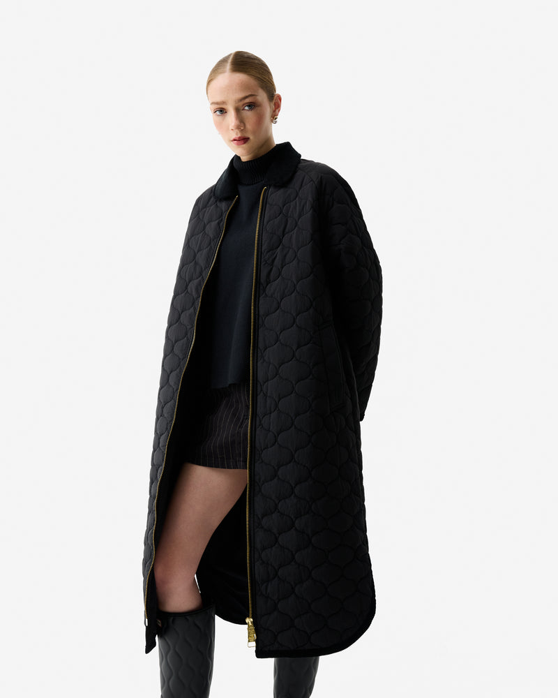 Displays a model wearing the Black Fionn 'Hunter' branded Women's Long Quilted Coat