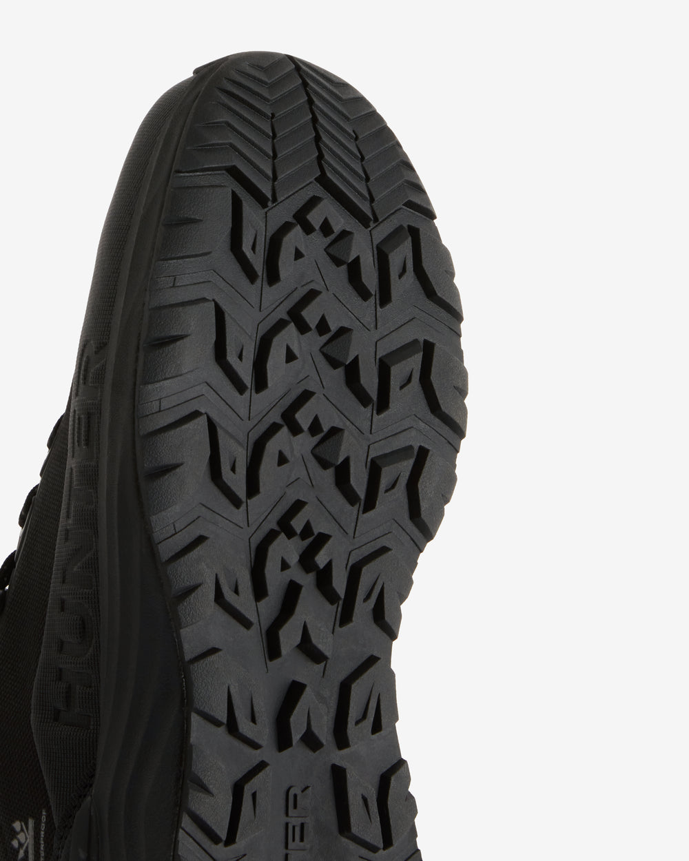Close-up of the black treaded outsole of a shoe against a light background.