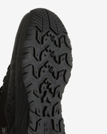 Close-up of the black treaded outsole of a shoe against a light background.