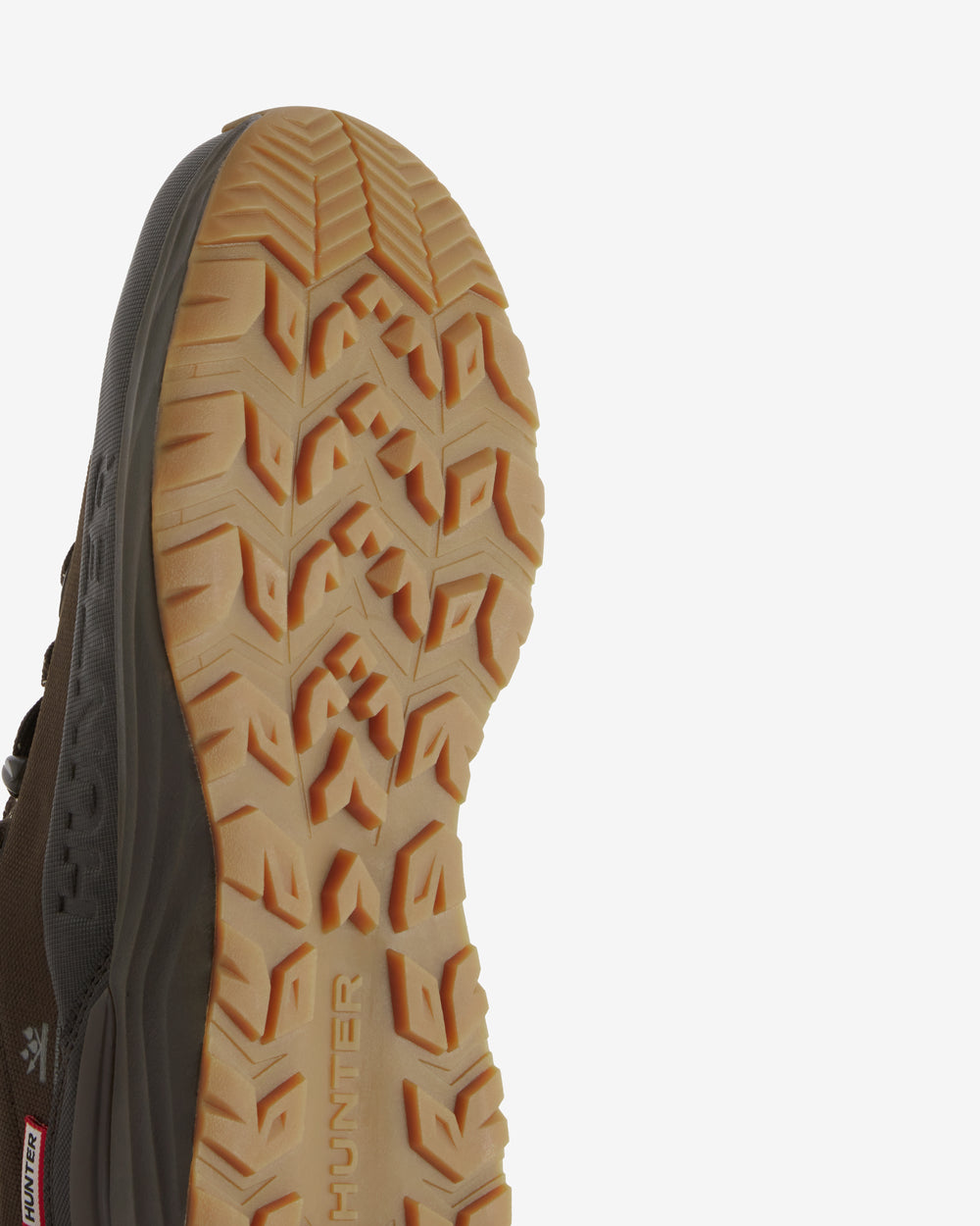 Close-up of the outsole of a Hunter hiking shoe, showing a tan and brown treaded rubber bottom with the Hunter brand name embossed vertically.