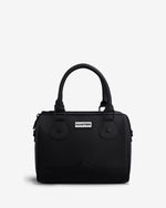 A black structured handbag with double top handles, a front flap pocket, and a small white Hunter brand plaque, photographed on a clean light gray background.