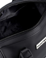 Close-up of a black duffel bag's open zipper compartment, showing the black interior lining and a silver metal brand plaque with the word HUNTER.