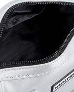 Close-up of a white bag's open zipper compartment, showing a black interior lining with subtle branding and black zipper trim.