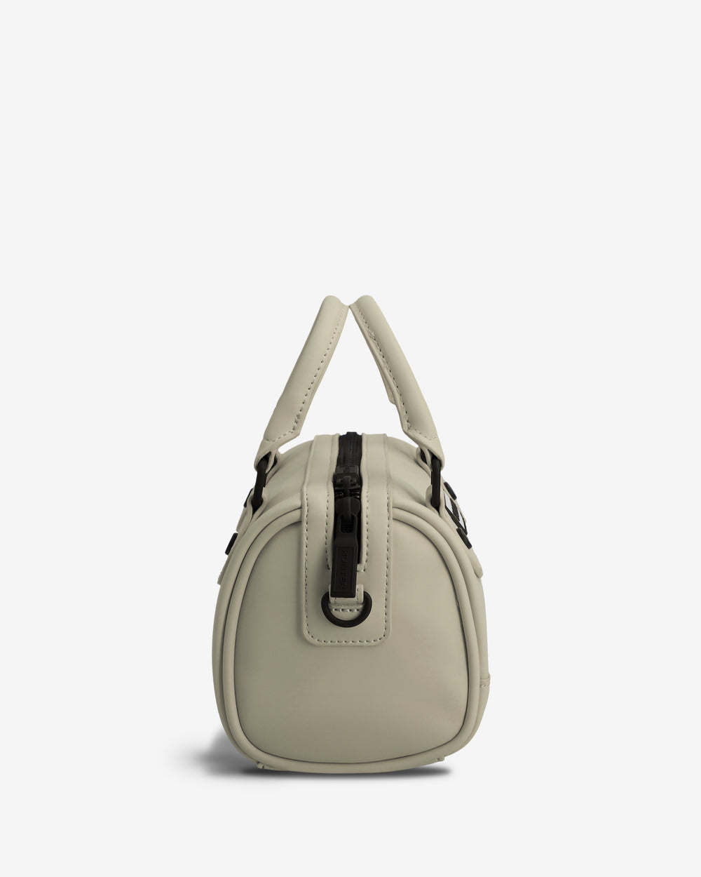 A light beige faux-leather handbag with a small dome shape, featuring dual top handles, a vertical black strap detail on the front, and silver-tone hardware, set against a plain white background.
