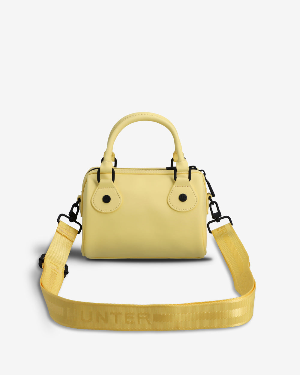 A light yellow structured handbag with a top handle, flap closure, and a matching wide shoulder strap laid flat in front. The strap has the brand name HUNTER printed across it.